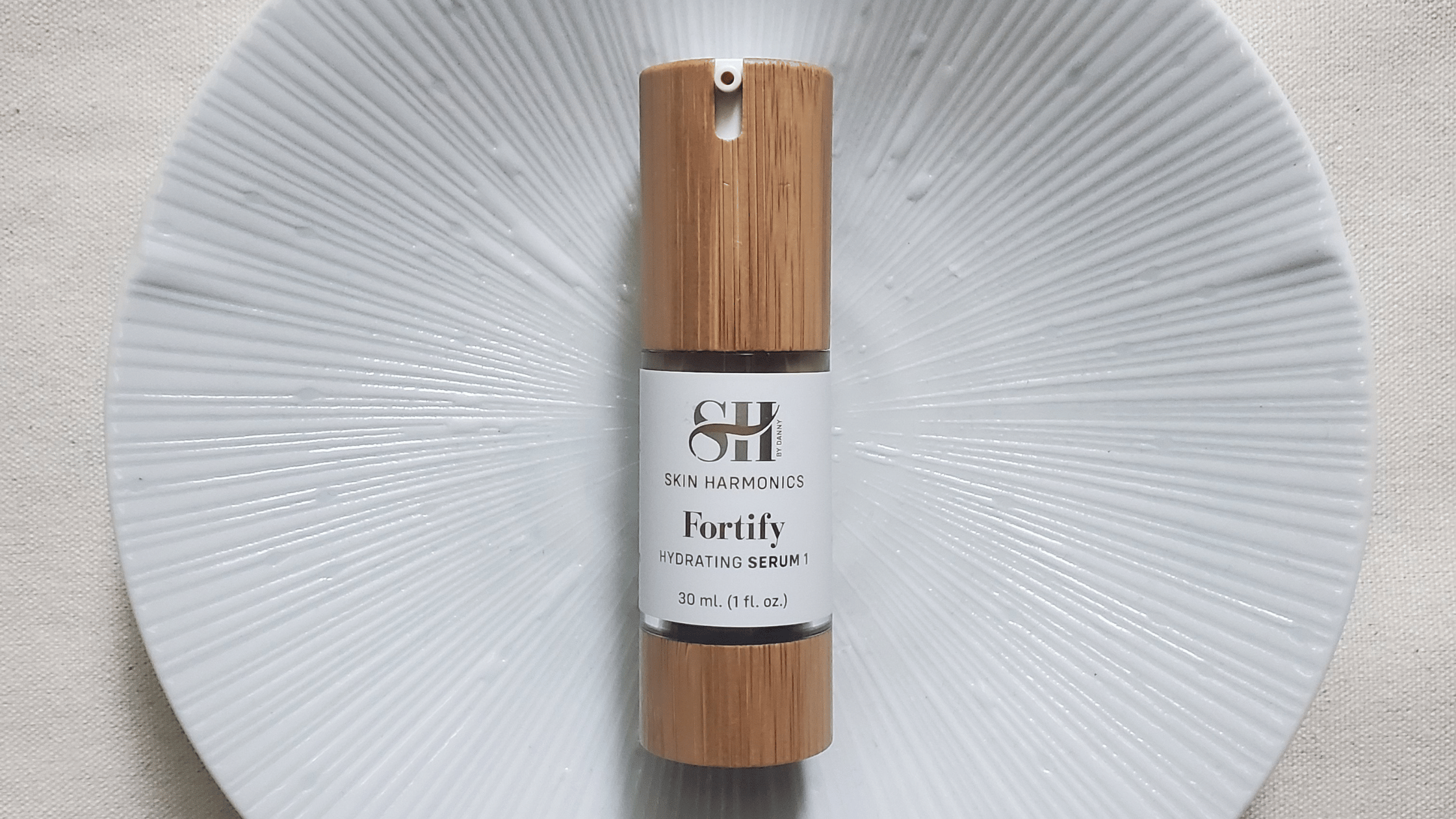 Skin Harmonics Fortify hydrating serum on a textured beige backdrop